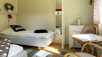 A bedroom with a bed, a desk, a chair, a dresser, and a window.