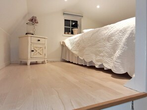 Quarto com cama, penteadeira, janela e radiador.