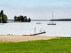 A calm lake with a dock extending into the water, surrounded by grassy areas and trees.
