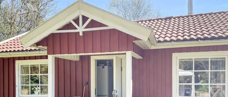 A single-story building with a red exterior, a white door, and a small porch area.