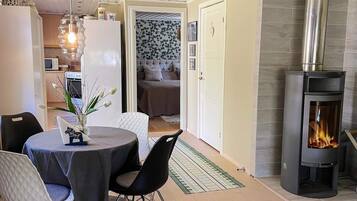 Una sala de estar acogedora con chimenea, un comedor con mesa y sillas, y una cocina al fondo.