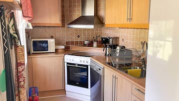 A compact kitchen with a microwave, stove, and sink.