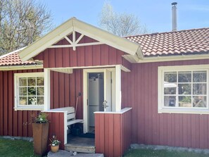 A red building with a white door, a small porch, and a window.