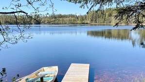 Une jetée en bois s’avance sur un lac paisible, et une petite embarcation est amarrée à son extrémité.