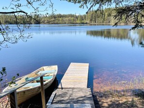 A wooden dock extending into a calm lake with a small boat docked at the end.