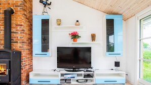 A living room with a TV, shelves, a fireplace, and a window. - 6 Person Holiday Home in Idestrup (Idestrup)