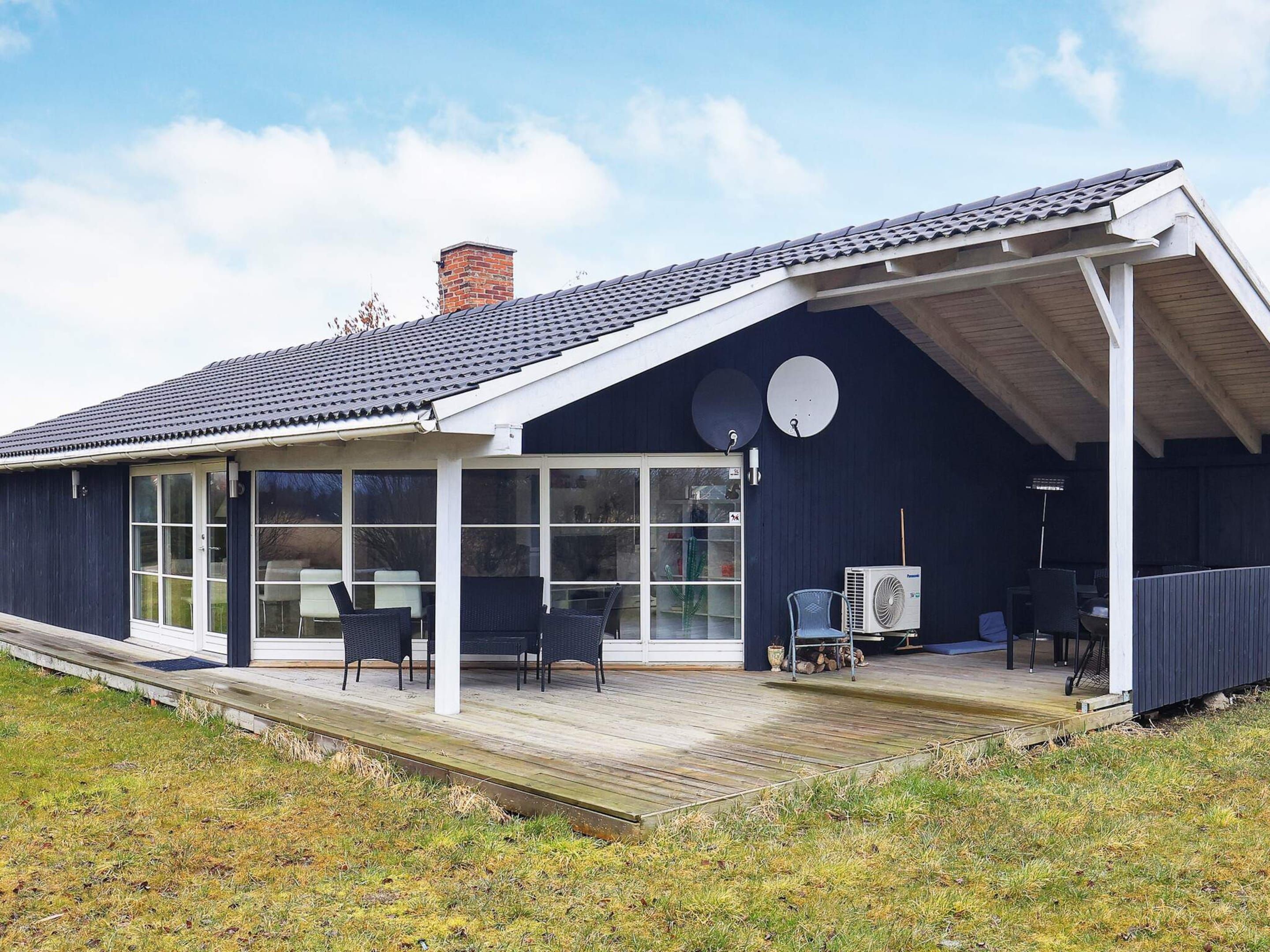 A modern house with a covered porch, large windows, and outdoor furniture.