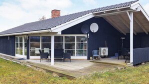 A modern house with a covered porch, large windows, and outdoor furniture. - 6 Person Holiday Home in Idestrup (Idestrup)