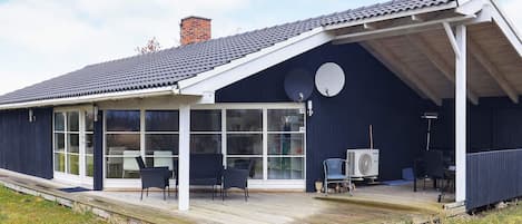 A modern house with a covered porch, large windows, and outdoor furniture.