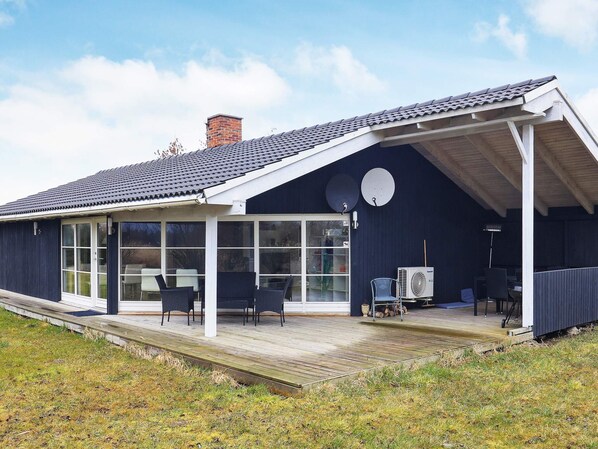 A modern house with a covered porch, large windows, and outdoor furniture.