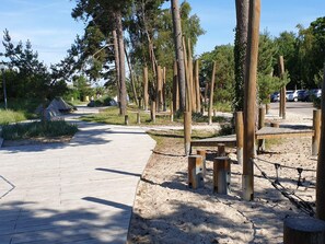 A paved walkway with wooden posts and benches, surrounded by trees and greenery. - 6 Person Holiday Home in Idestrup (Idestrup)