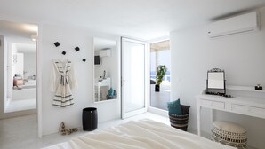 Quarto moderno com uma cama grande, uma penteadeira com espelho e vista para o exterior.