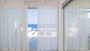 Quarto com amplas janelas e vista para o mar.