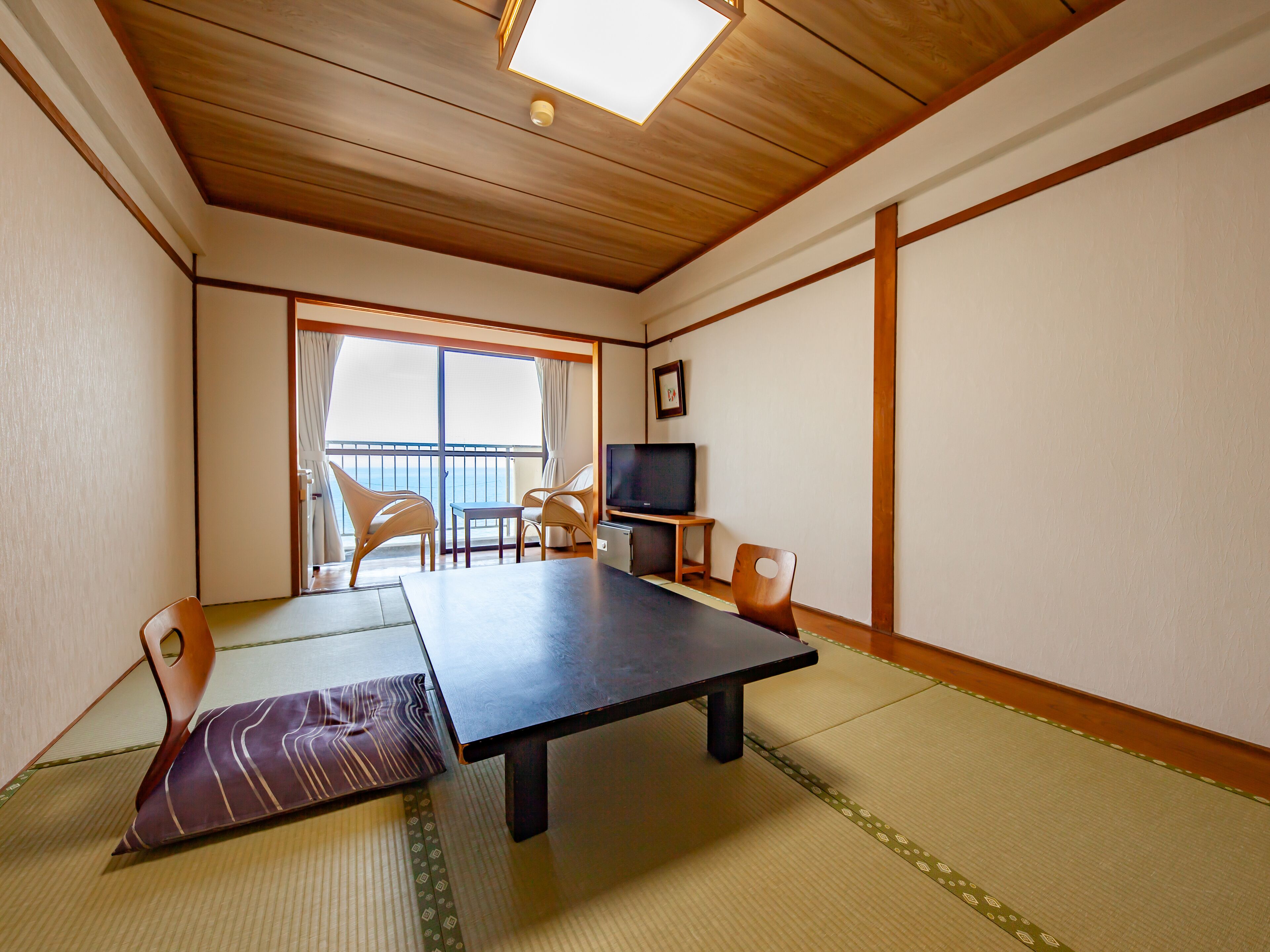 A traditional Japanese room with tatami flooring, a low table, and chairs.