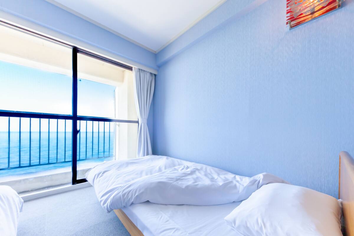 A hotel room with a bed, a view of the sea, and a balcony.