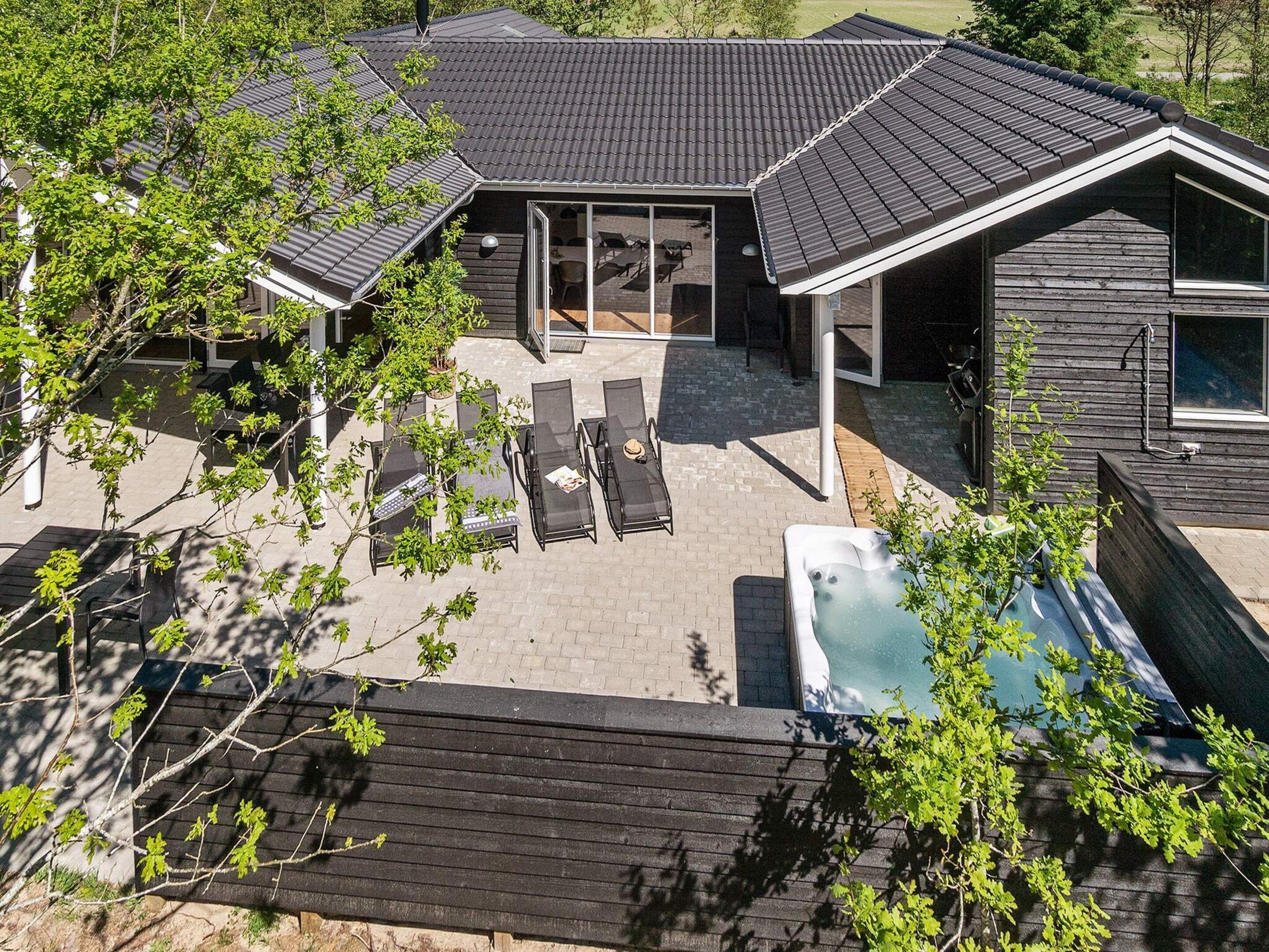Een modern huis met een patio, buitenzitplaatsen en een jacuzzi.