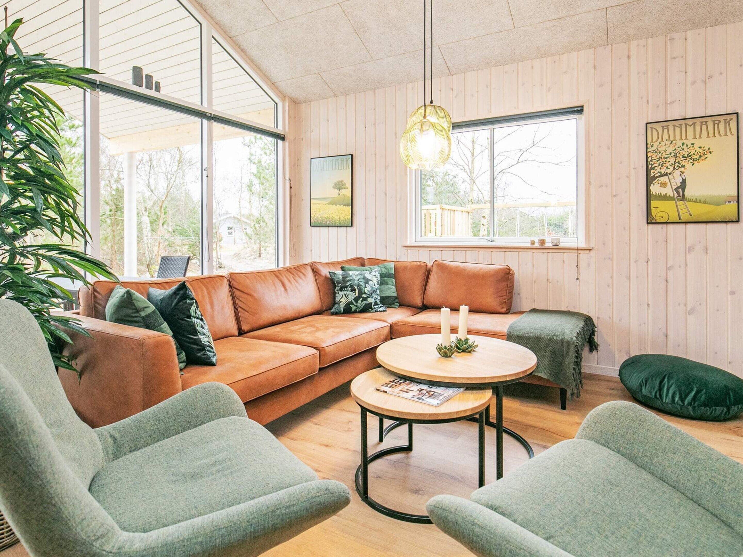 A cozy living room with a leather sofa, two armchairs, a round coffee table, and a hanging light fixture.