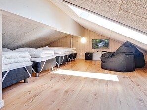 A loft bedroom with a sloped ceiling, wooden flooring, a television, and a bean bag chair. - 5 Star Holiday Home in Fjerritslev (Fjerritslev)