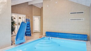 Ein Hallenbad mit einer blauen Rutsche, einer Leiter und einer Sitzbank.