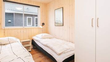 A room with two beds, a window, a wall-mounted lamp, and a wardrobe.