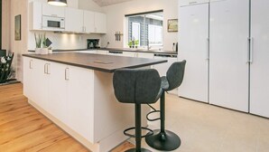 A modern kitchen with a central island, bar stools, and a skylight.