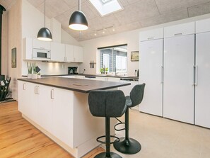 A modern kitchen with a central island, bar stools, and a skylight.