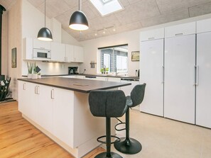 Eine moderne Küche mit einer zentralen Kochinsel, Barhocker und einem Oberlicht.