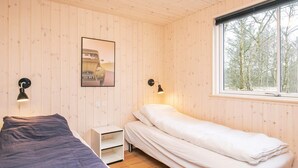 A room with two beds, a window with a view of trees, and a wall-mounted picture.