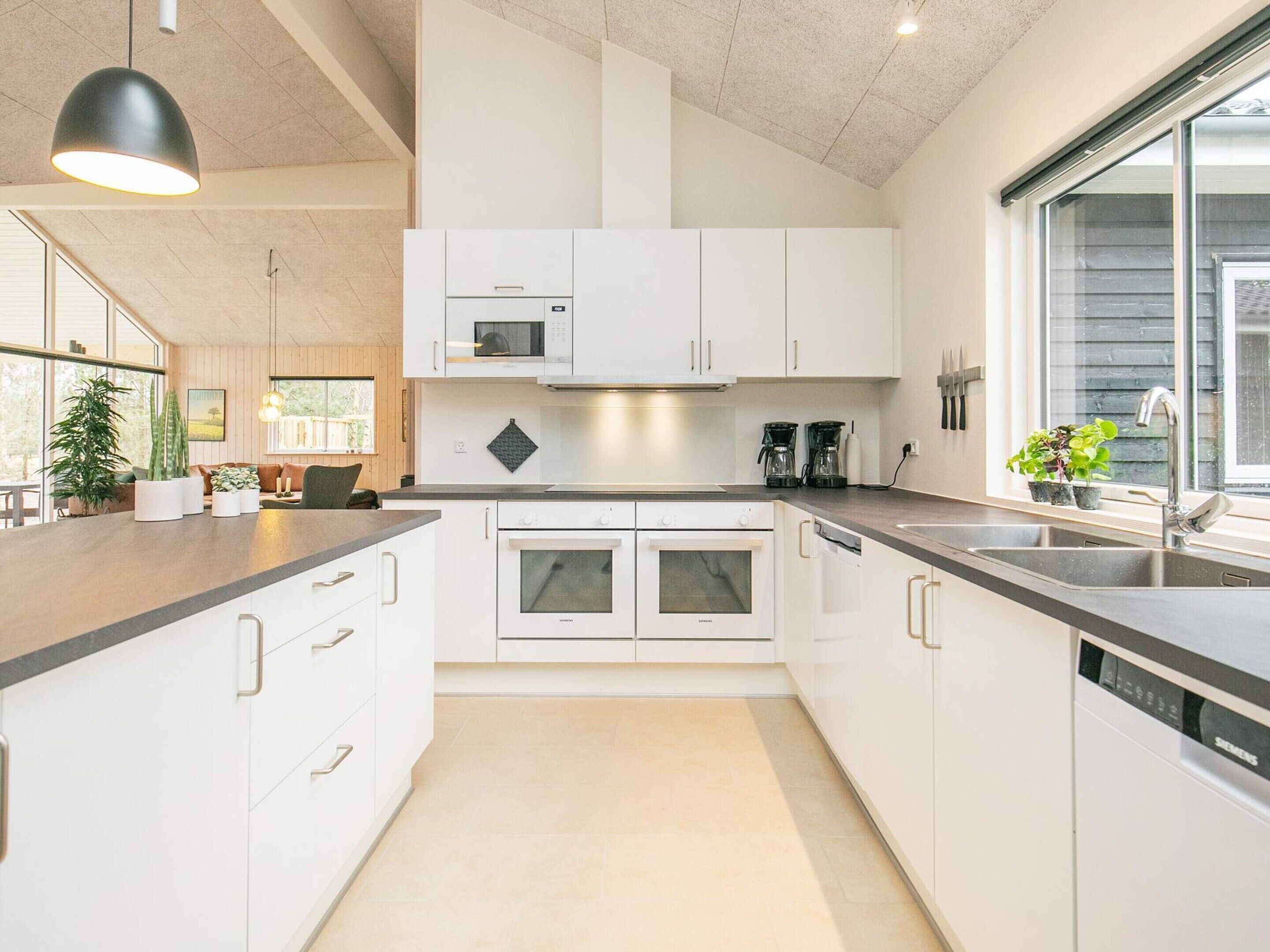 A modern kitchen with white cabinets, a built-in oven, and a dishwasher.
