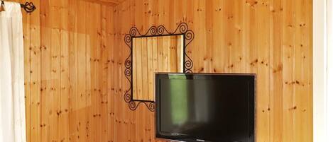 A room with wooden walls, a television on a stand, a curtain, and a ceiling light fixture.