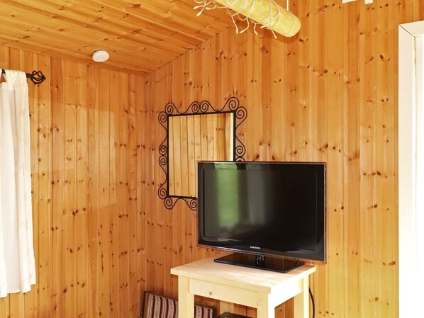 A room with wooden walls, a television on a stand, a curtain, and a ceiling light fixture.
