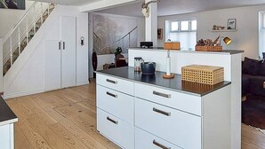 A modern kitchen with white cabinetry, a wooden countertop, and a staircase leading to another level.