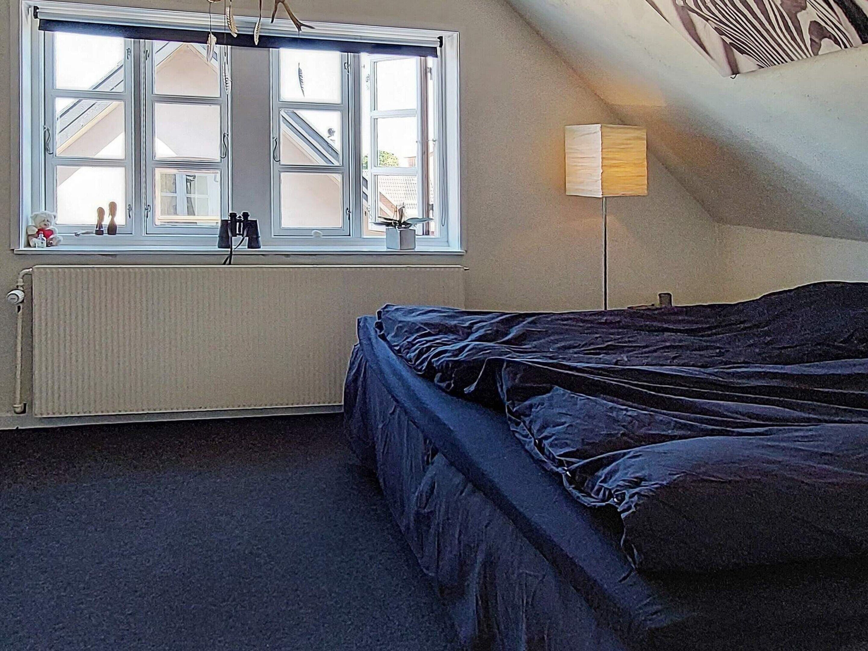 Makuuhuoneessa on yksi sänky, patteri, ikkuna ja lamppu.