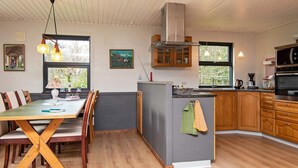 A modern kitchen with wooden cabinets, a central island, and a dining area with a wooden table and chairs. - 8 Person Holiday Home in Romo (Rømø)