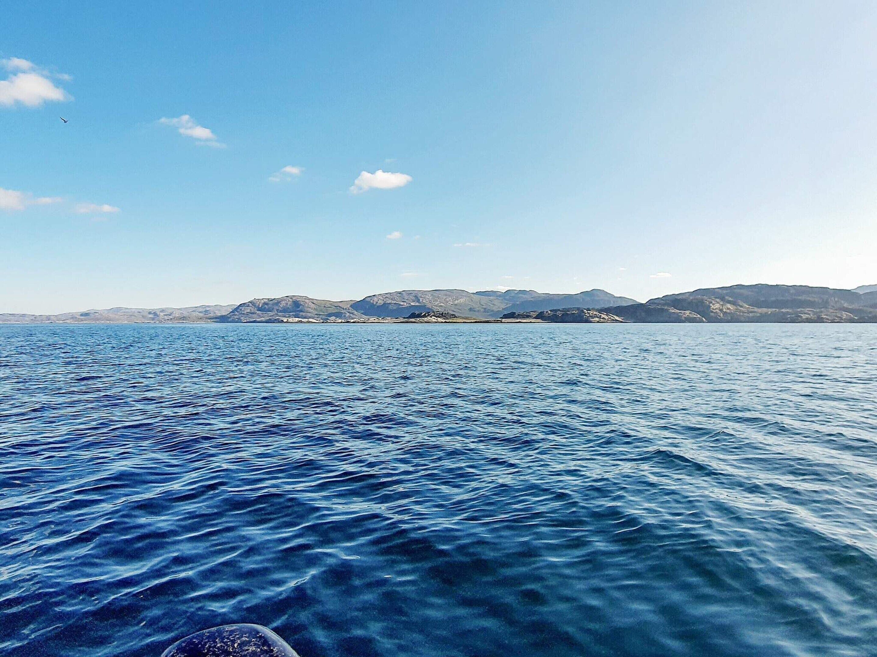 A calm sea with mountains in the background.
