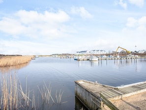 A calm waterfront with docked boats, a crane, and residential buildings in the background. - 6 Person Holiday Home in Tarm (Tarm)