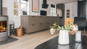 A modern kitchen with a fireplace, wooden cabinets, and a dining area with a table and chairs. - 6 Person Holiday Home in Tarm (Tarm)