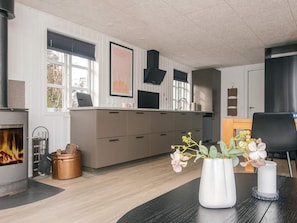 A modern kitchen with a fireplace, wooden cabinets, and a dining area with a table and chairs.