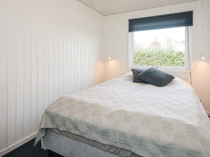A small, single-bed room with a window, white walls, and a visible outdoor view.
