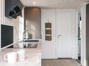 A modern kitchen with a built-in stove, a sink, and a countertop. There are two mugs on the counter.