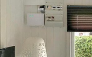 A utility panel with electrical components, a thermostat, and a window with blinds.