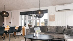 A modern living room with a sofa, a coffee table, and a dining area with chairs and a table. - 6 Person Holiday Home in Tarm (Tarm)