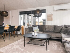 A modern living room with a sofa, a coffee table, and a dining area with chairs and a table.