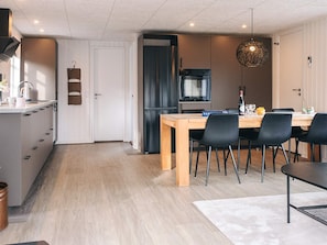 Eine moderne Küche mit Essbereich, einem Kühlschrank und einer Hängelampe.