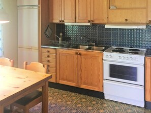 A kitchen with wooden cabinets, a stove, and a refrigerator. - 4 Person Holiday Home in Rorvik (Rörvik)