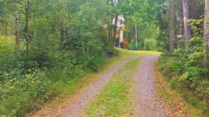 Un sendero de grava que lleva a una casa rodeada de un bosque denso.