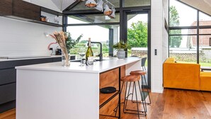 Una cocina moderna con una isla central, taburetes de bar y vistas al exterior.