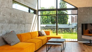 Una sala de estar moderna con un gran ventanal, un sofá, una mesa de centro y un televisor.