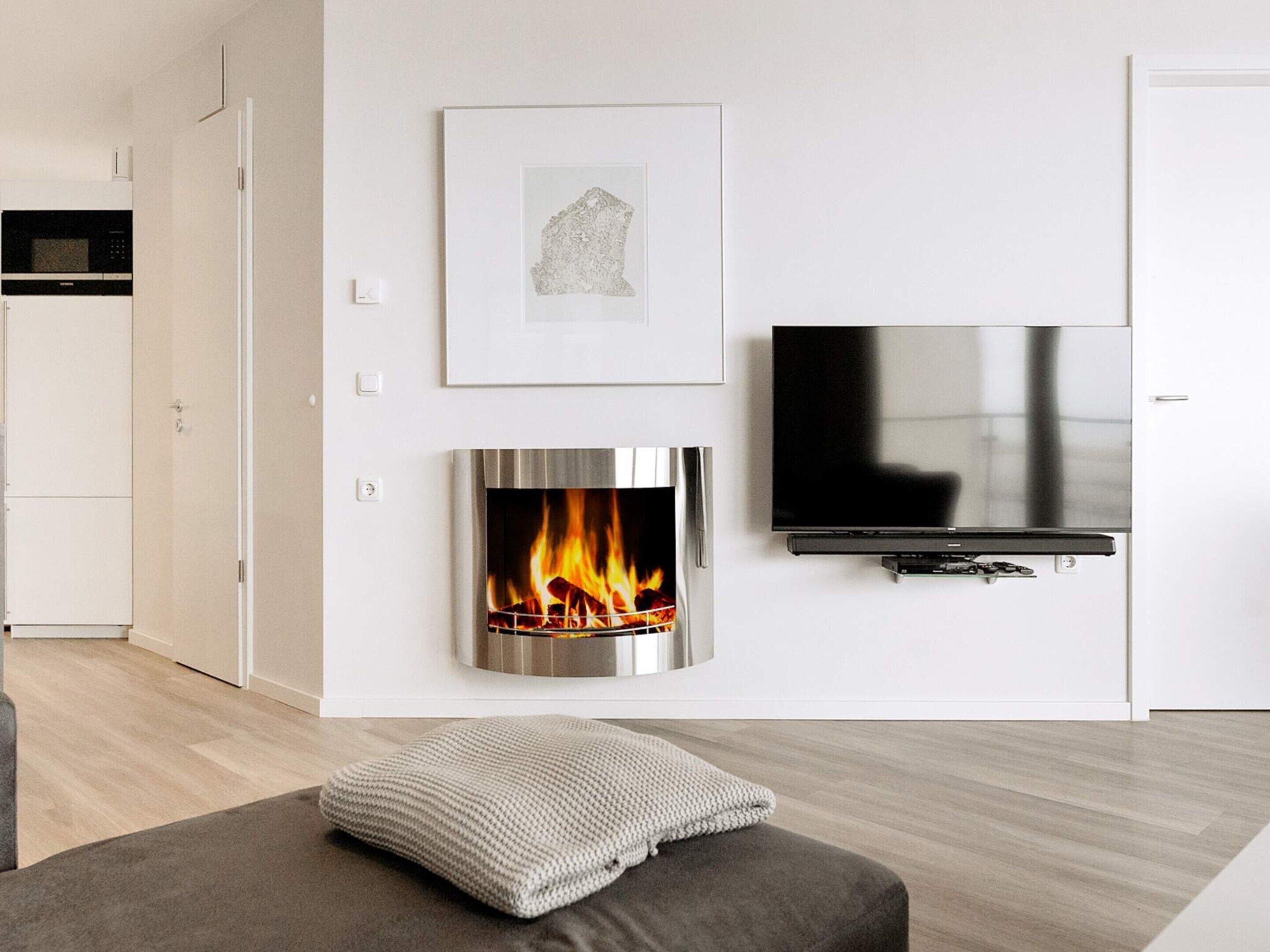 A modern living room with a fireplace, a flat-screen TV, and a cozy seating area.