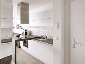 A modern kitchen with white cabinetry, a stainless steel sink, and a built-in oven.